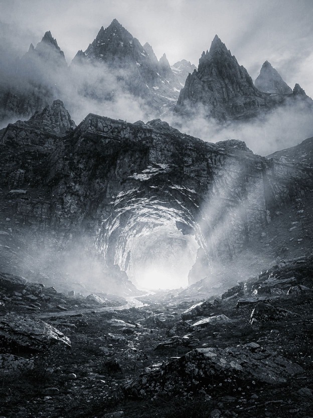 mysterious ancient cave entrance glowing with ethereal light in misty mountain landscape