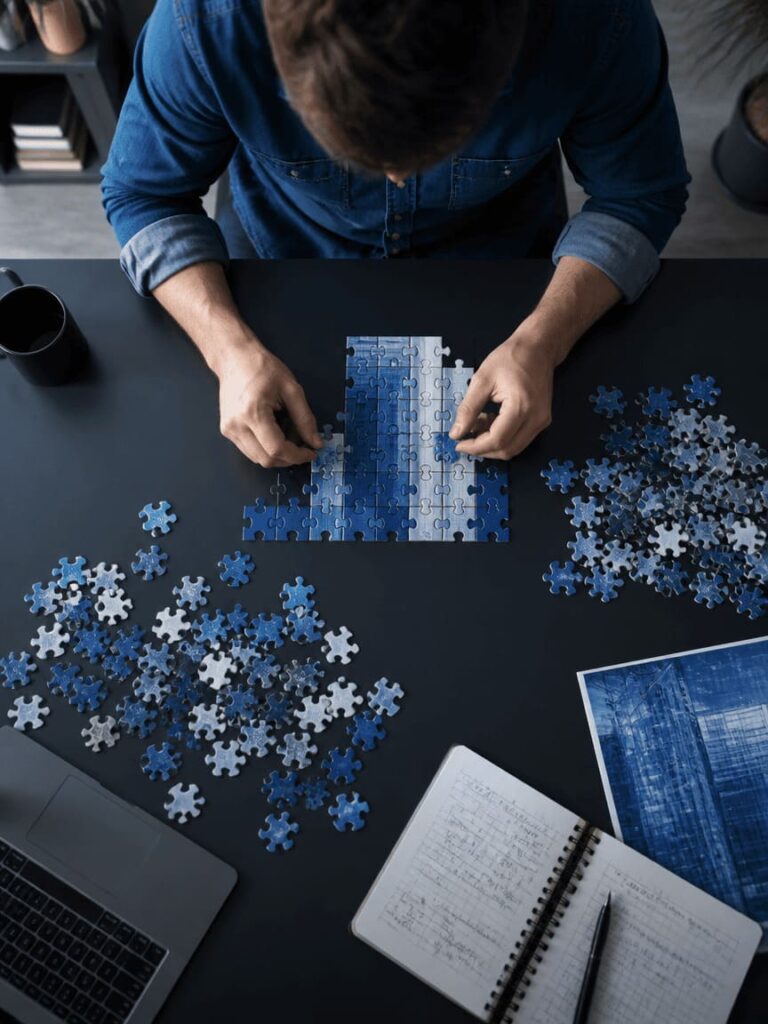 person selectively picking puzzle pieces that fit, leaving others aside, top view